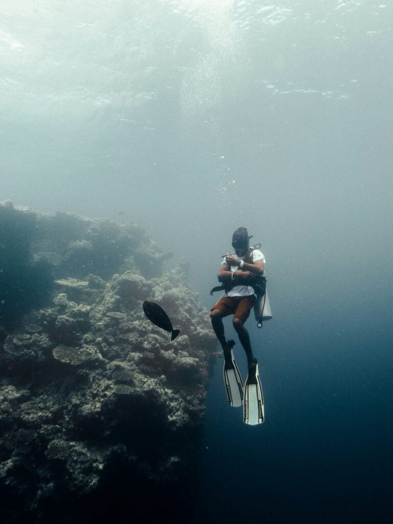 Ein Taucher erkundet die lebendige Unterwasserwelt in der Nähe von Gulhi, Malediven, umgeben von farbenfroher Meeresfauna.
