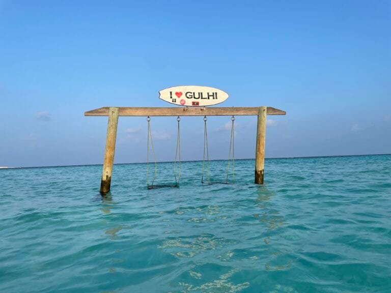A swing hanging over water with a sign above it, set in the beautiful Maldives, Gulhi.
