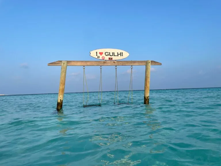 A swing hanging over water with a sign above it, set in the beautiful Maldives, Gulhi.